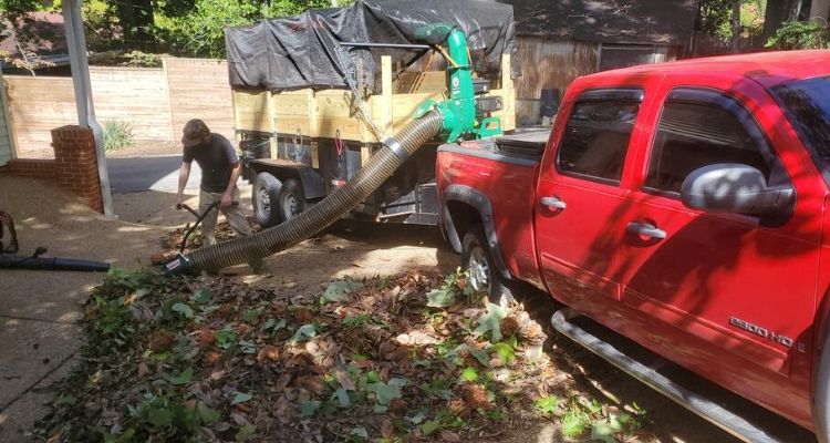 Lawn maintenance company in Birmingham removing leaves with their leaf vacuum and truck and trailer.